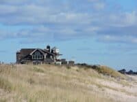 A house on the beach with a crane in the background.
